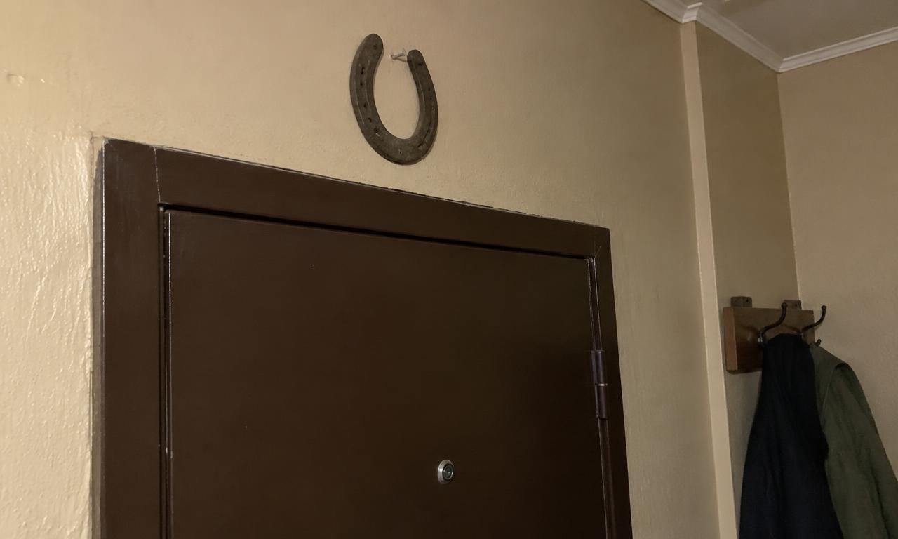 Un vieux fer à cheval fixé juste au-dessus d'une porte d'entrée d'appartement.